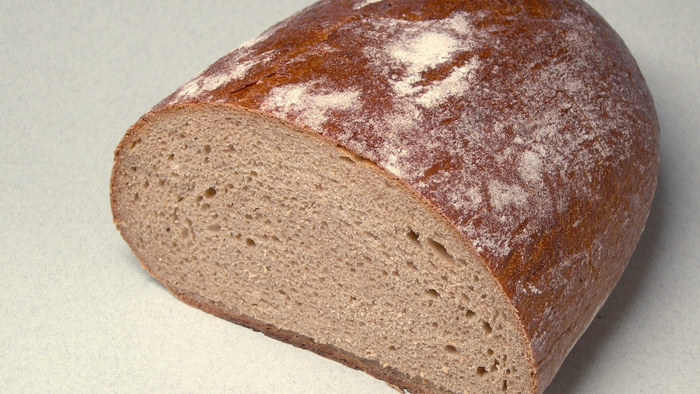 Ein Stück Vollkornbrot liegt auf einer weißen Oberfläche