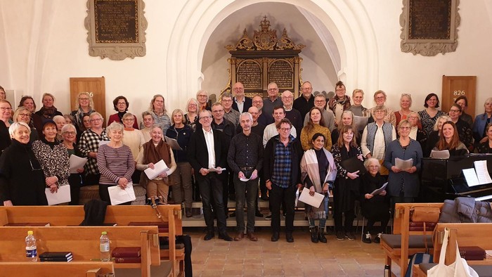 En stor gruppe af mennesker samlet i kirke, alle med blæserpartiturer.