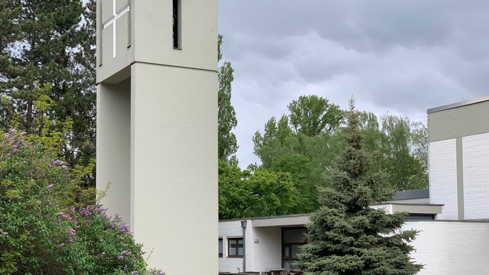 Ein modernes Gebäude mit hohem Turm und umgebender Natur.