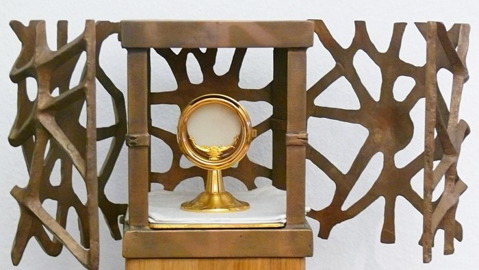 Komplexer Holzvitrinen-Schaukasten mit einem goldenen Kelch und einer Patene auf einer Holzunterlage.
