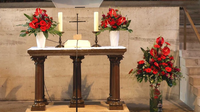 Ein Altar mit roten Blumen und Kerzen in einer Kirche