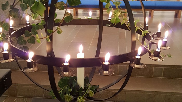 En stor blomst i en vase foran et lyskugle med lys.