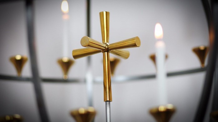Guldfarvet kors med lysende lys i baggrunden