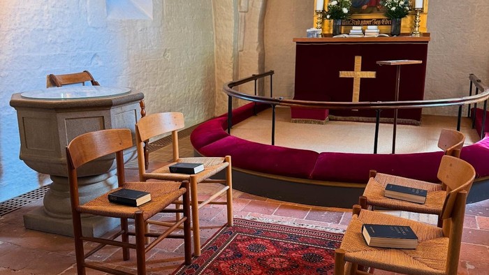 To stolepar er opstillet overfor hinanden foran alteret, som ved en vielsesceremoni.