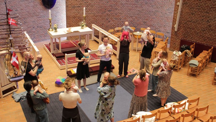 En gruppe udfører en dans inde i en kirke under en festlig eller fællesskabsbegivenhed.