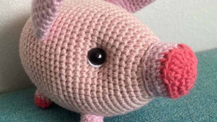En rosa håndkøret svin med rosa øre og føde.