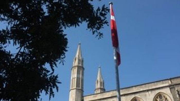 En kirke med to tårne og en rød flag på en stang.