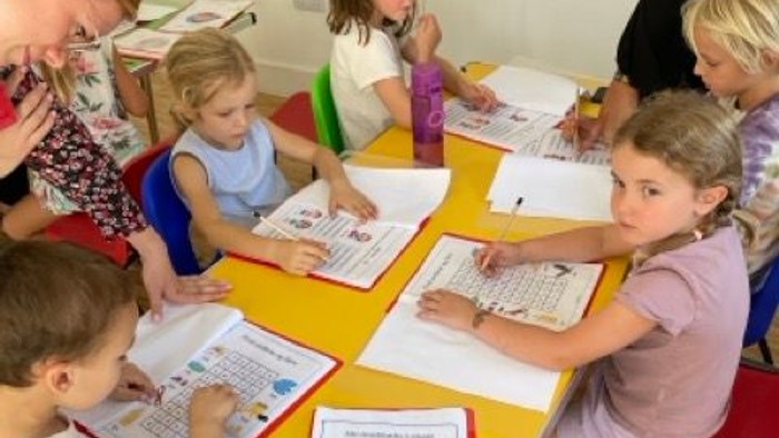 Børn sidder om bord og arbejder med papirer i skoleklassen