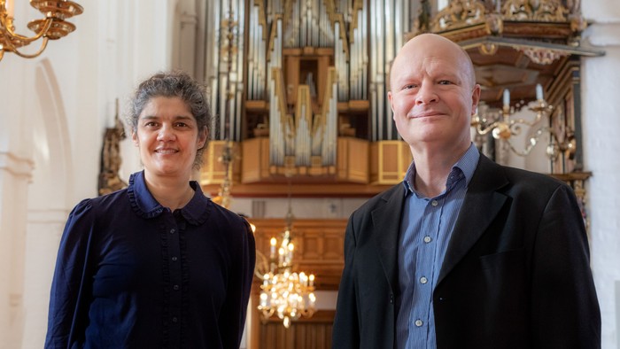 To og en mand står foran en orgel i kirke.