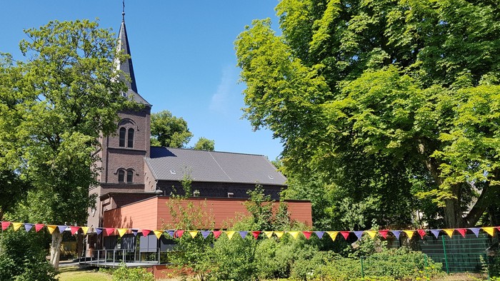Eine charmante Kirche, umgeben von üppigem Grün mit farbenfrohem Girlandenbannern, die über die Fläche gespannt sind.