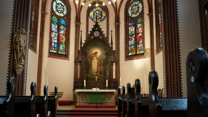 Elegante Kircheninnenausstattung mit Buntglasfenstern, Altar mit religiösen Kunstwerken und hölzernen Kirchenbänken.