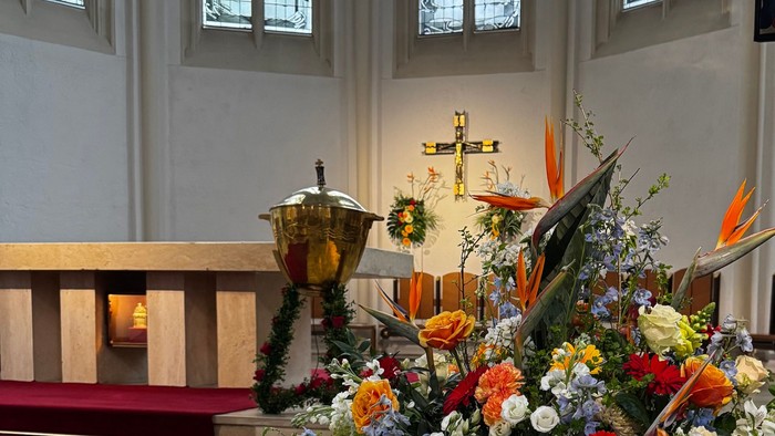 Blick durch die Blumen auf das Taufbecken in den Altarraum von St. Matthias