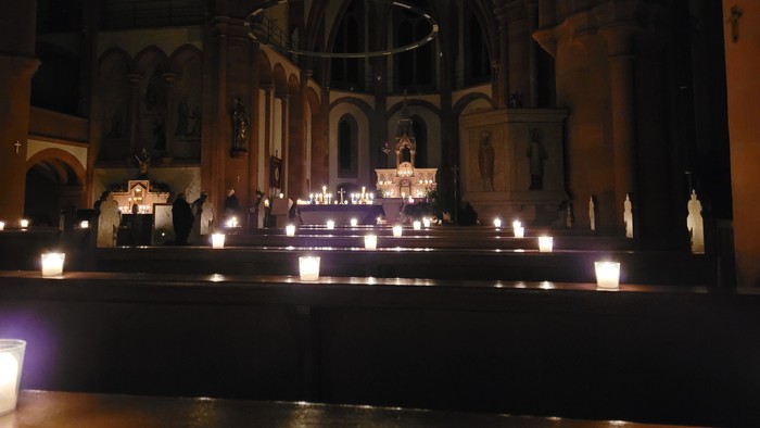 Kircheninneres mit brennenden Kerzen und religiösen Statuen.