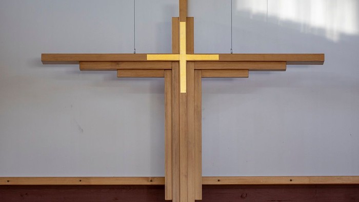 En stor, gul korsformet pryd på en hvide mur med et vindue ovenfor
