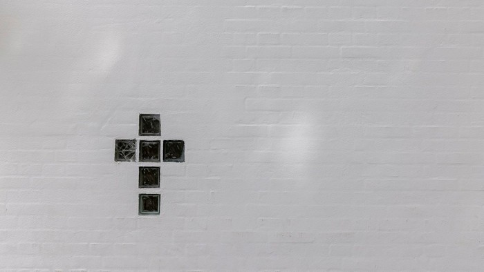 En sort krydsformet figur på en lys mur