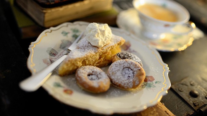 Ein Teller mit Gebäck und ein Tee in einer Porzellantasse auf einem Tisch