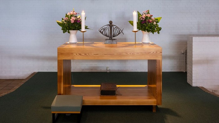 En moderne kirkeinteriør med alter, lys og blomster.