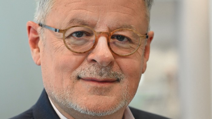 Ein älterer Mann mit Brille und Anzug.