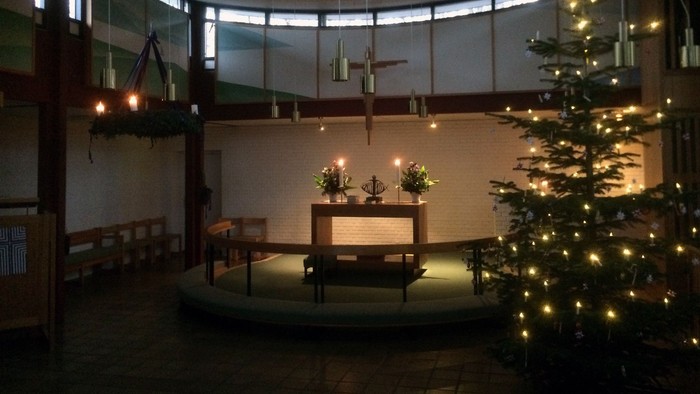 En lysset kirkeindgang med juletree og alter med lys.
