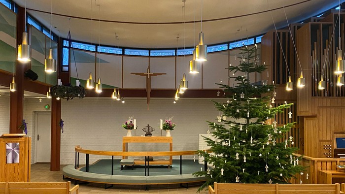 Indre del af kirke med juletree og lys.