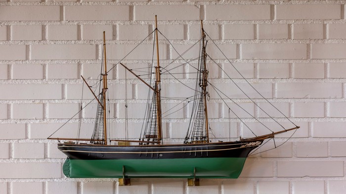 Et smukkt modelleret skib monteret på en hvid mursten.