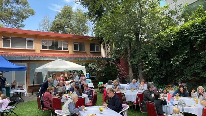 Eine Gruppe von Menschen sitzt im Freien an Tischen und isst.