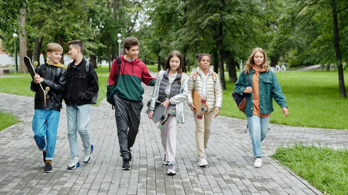 Eine Gruppe von Jugendlichen geht auf einem Kopfsteinpflasterweg im Park.