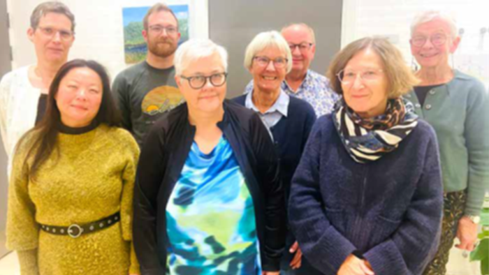 En gruppe af syv personer står sammen og smiler til kameraet