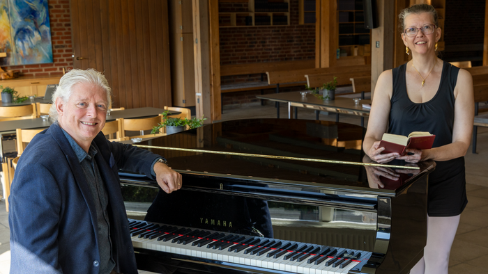 En mand sidder ved et piano, en kvinde står ved siden af ham med noter