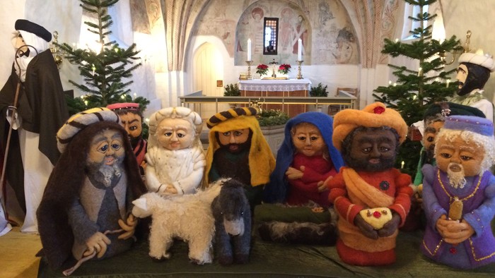 En rekke nisser sidder på alteret i en kirke