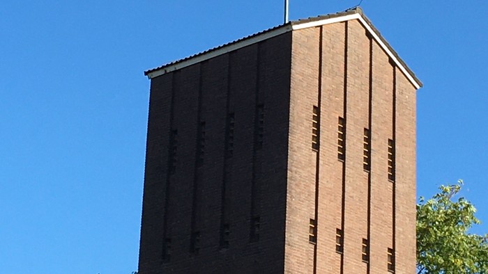 Kirchturm mit Kreuz vor blauem Himmel