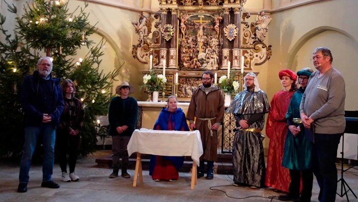 Eine Gruppe von Menschen posiert vor einer Krippe in einer Kirche