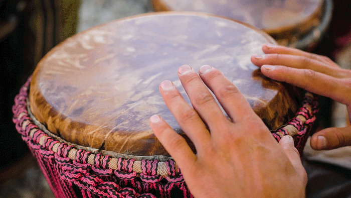 Zwei Hände trommeln auf einer Djembe