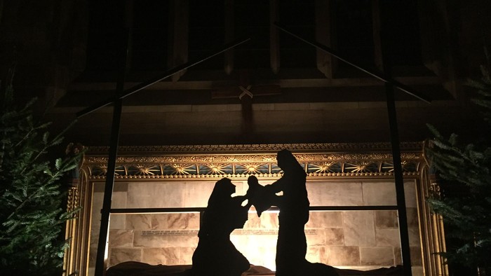 Silhouettes of three figures in a lit display, likely a nativity scene.