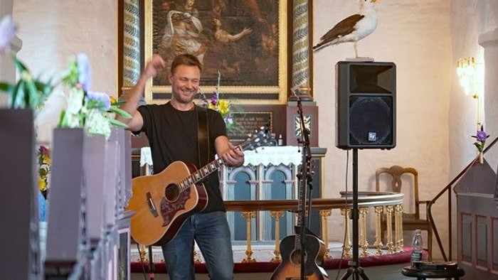 En mand spiller guitar i en kirke.