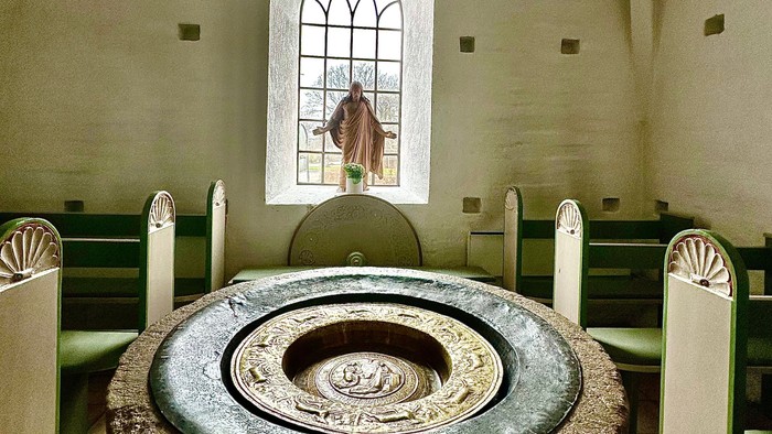 En kirke med en stor stenfont og hvidt bænke.