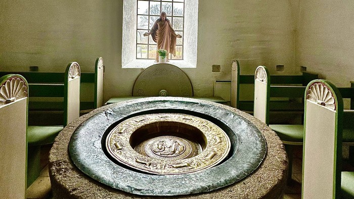 En kirke med en stor stenfont og hvidt bænke.