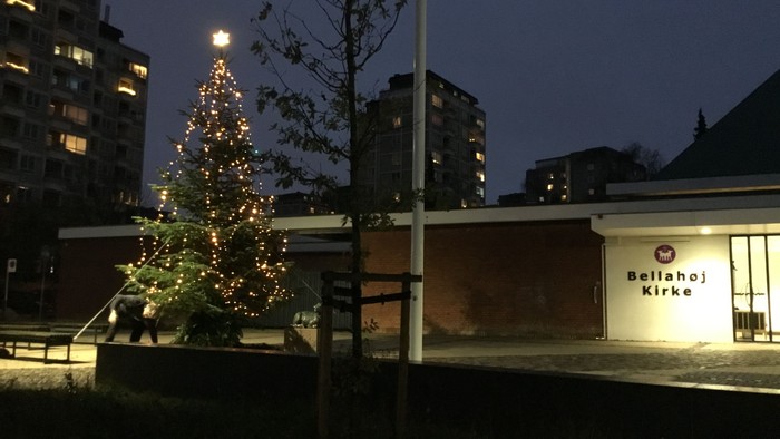 En juletree belyset med lys i en lille park ved et hus med navnet Ballahoj Kirke