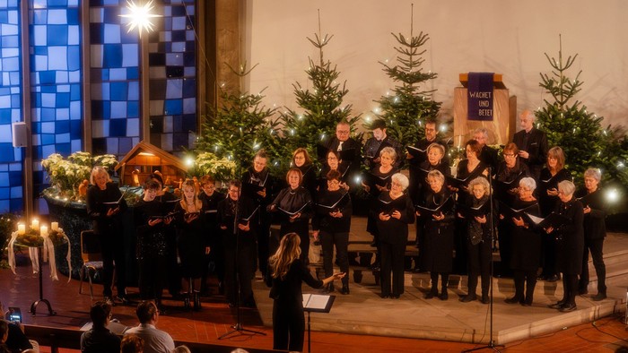 Kirchenchor tritt auf der Bühne mit Weihnachtsdekoration auf.