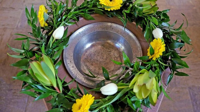 Eine Blumenanordnung umgibt eine Metallschale mit Sand.
