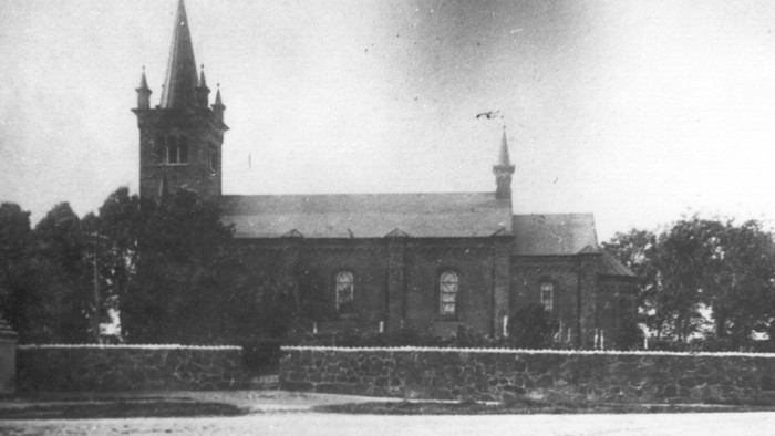 En gammel kirke med to tårne og murvej tilgåelse