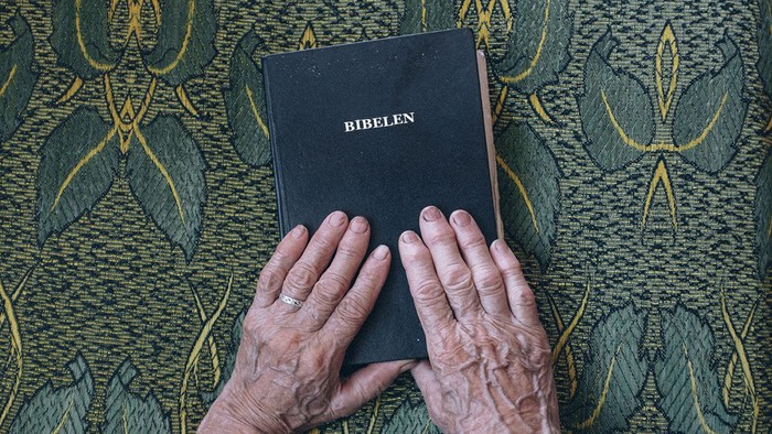 En person holder en bibel på sine knæ.