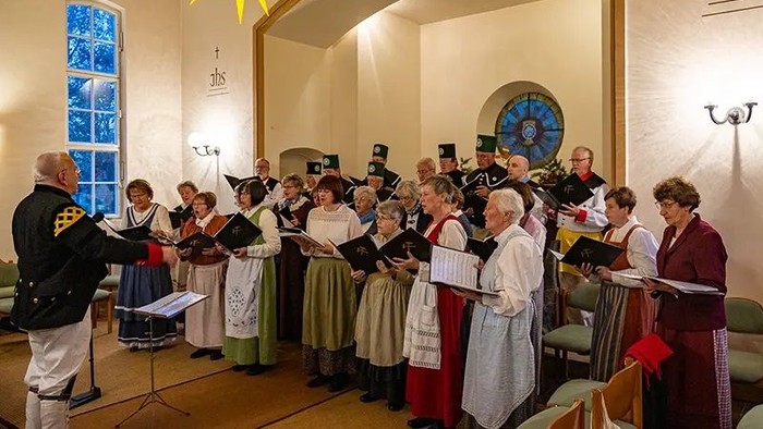 Ein Kirchenchor singt unter der Leitung eines Dirigenten in einer Kirche.