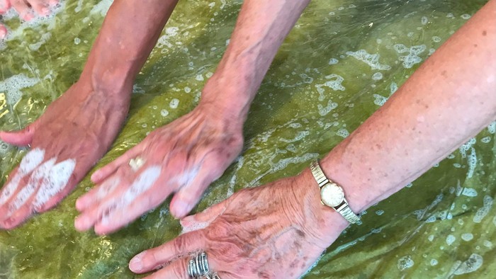To hands med smud og armbåndur i vand