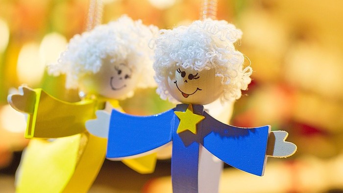 To små englefigurer med hvidt hår og blå kåber, hvor den ene holder en gul stjerne.