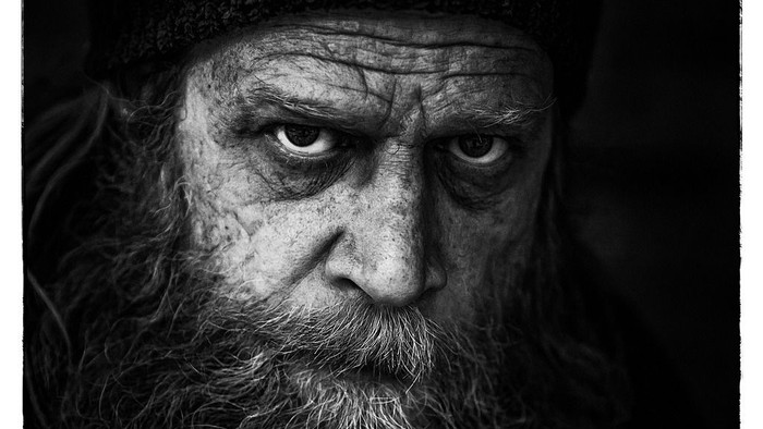 Et slående sort-hvidt portræt af en intens, skægget mand med dybe rynker og et alvorligt udtryk.