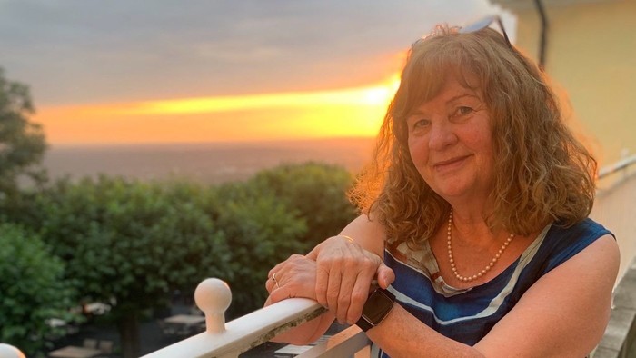 Ingrid Schütte-Nießen lehnt sich an ein Geländer und schaut in den Sonnenuntergang