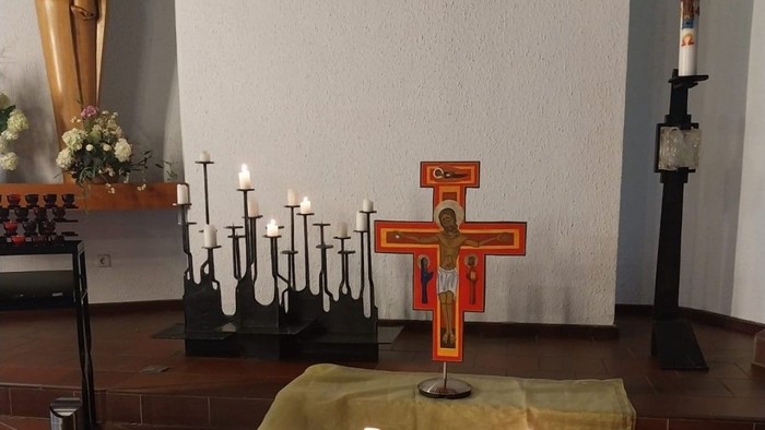 Ein Kreuz mit Kerzen und einer Marienstatue in einer Kirche