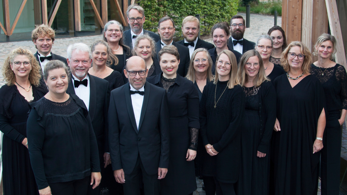 En gruppe af 20 personer, alle i formel klædning, står sammen på en fladt pave.