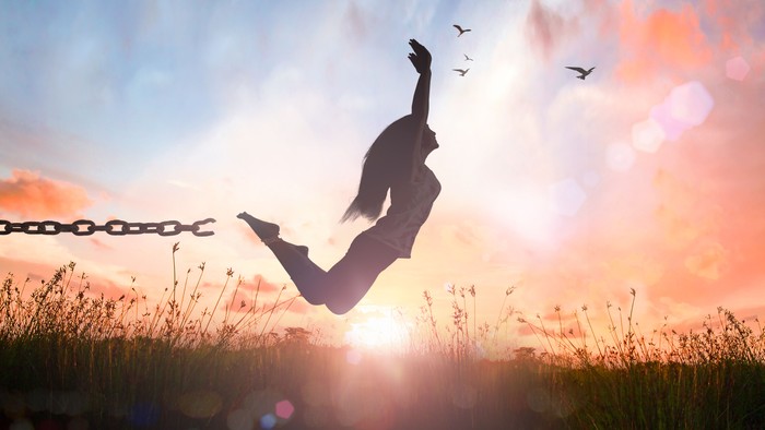 Person springt frei mit Ketten in Sonnenuntergang